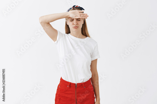 Portrait of troubled upset good-looking woman in stylish clothes whiping sweat off forehead and frowning, breathing out with closed eyes being distressed and tired of working all day photo