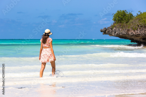 Young woman wearing a hat in a amazing blue water beach in Zanzibar in Tanzania