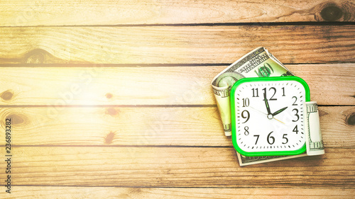 Clock and money on wooden background. Time is money