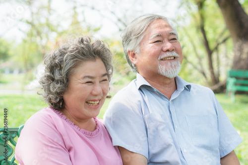 Asian healthy senior couple relaxing seated in the park together. © Pormezz