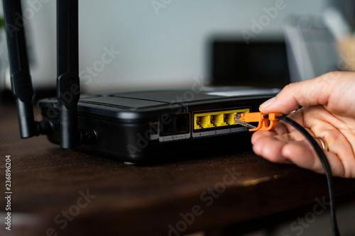 Obraz na płótnie Man plugging in an ethernet cable to a wireless router
