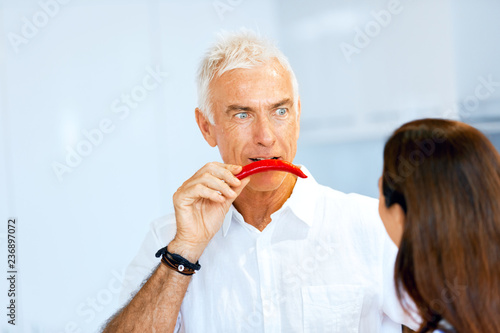 Man holding a red pepper next to his face