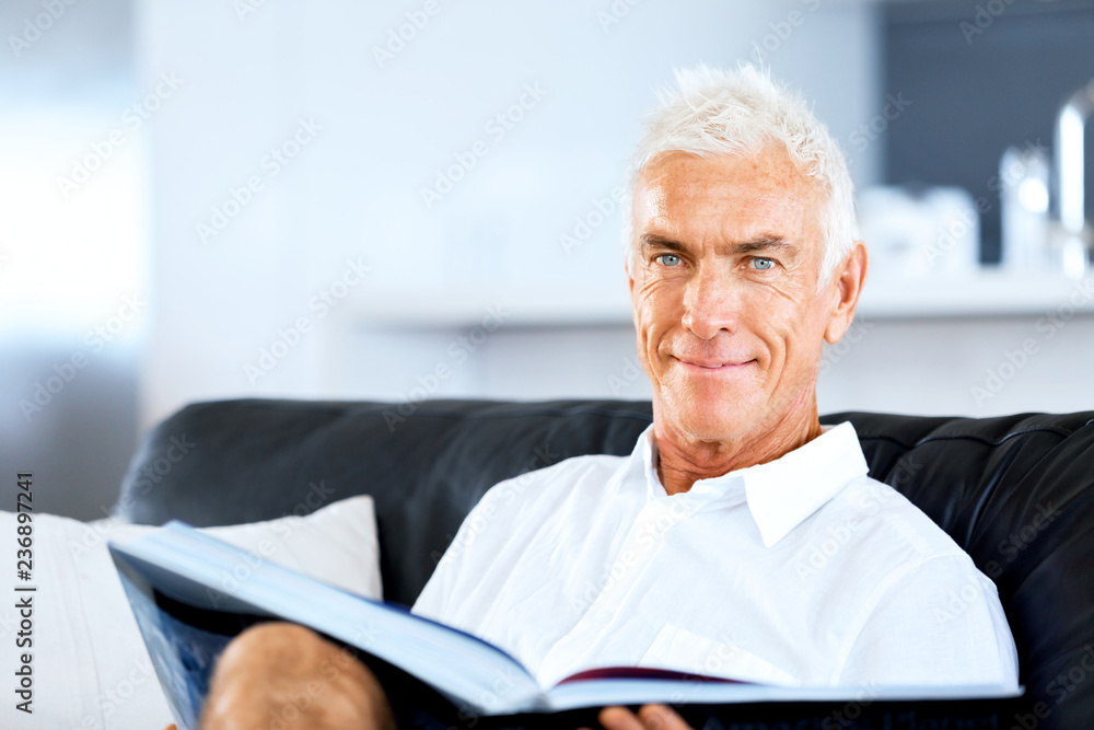 Handsome sennior man reading a book relaxing on a sofa Handsome sennior man reading a book relaxing on a sofa