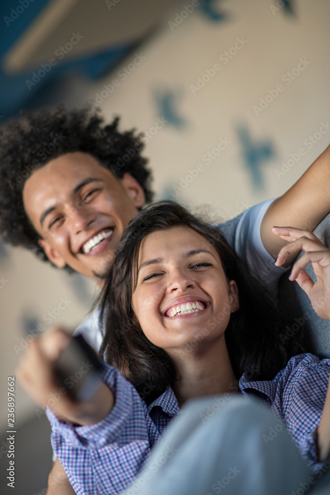 Obraz premium Young black couple relaxing on couch and smiling at camera