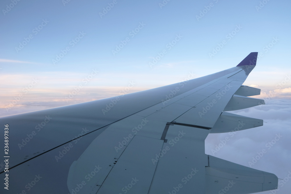 Wing of airplane above the cloud in the blue sky