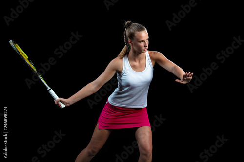 Portrait of beautiful woman playing tennis indoor. Isolated on black.