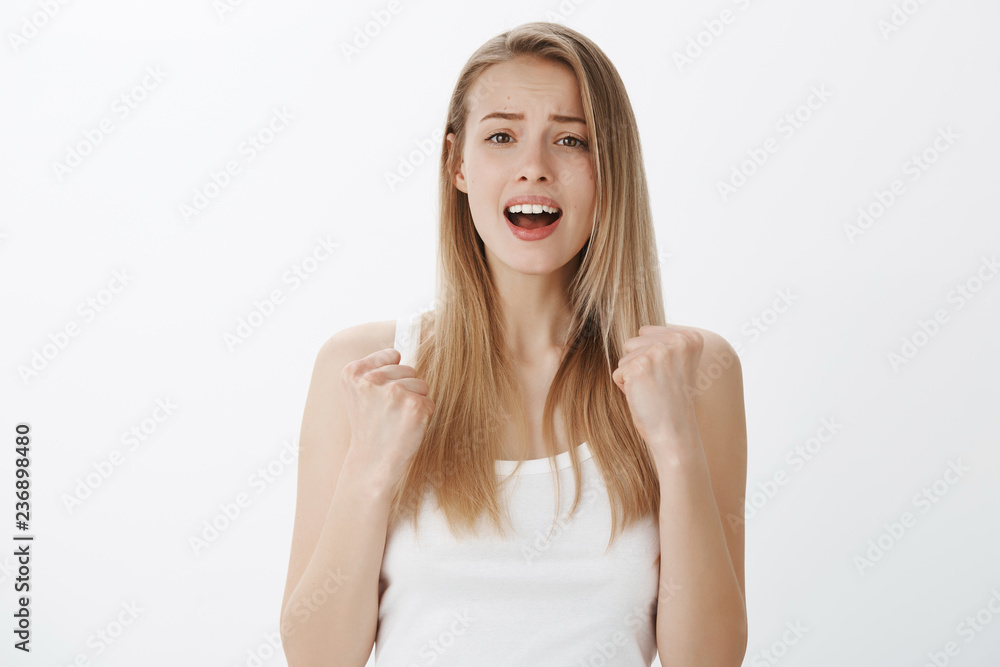 Girl desperatly cheers for friend putting effort to yell supportive words looking with hope at camera open mouth and frowning, clenching fists in victory and tirumph waiting for final score Girl desperatly cheers for friend putting effort to yell supportive words looking with hope at camera open mouth and frowning, clenching fists in victory and tirumph waiting for final score