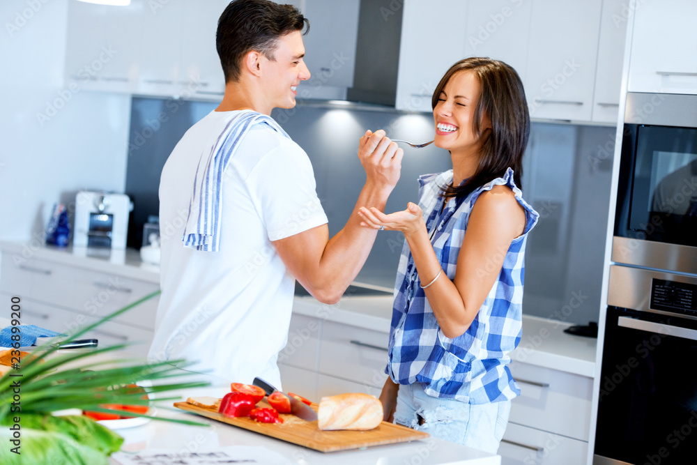Young couple in the kitchen tasting food