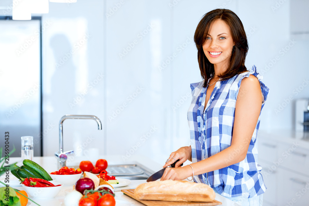 Beautiful woman standing in the kitchen and smiling Beautiful woman standing in the kitchen and smiling