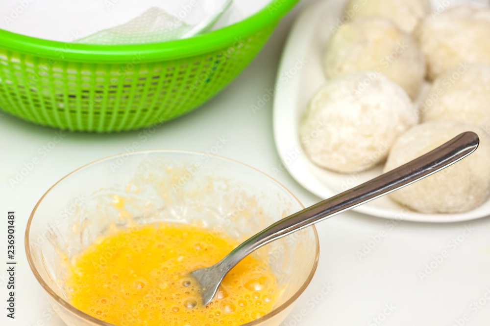 Preparation steps of traditional Colombian dish called stuffed potatoes: Dunking stuffed potatoes in egg and flour mixture Preparation steps of traditional Colombian dish called stuffed potatoes: Dunking stuffed potatoes in egg and flour mixture