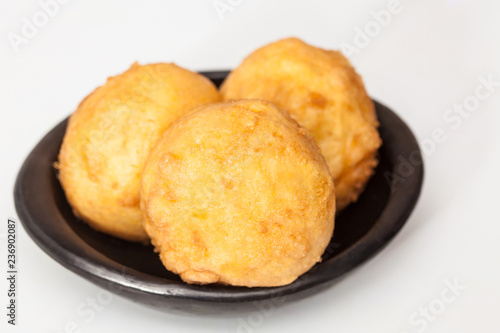 Preparation steps of traditional Colombian dish called stuffed potatoes : Ready stuffed potatoes served in a black ceramic dish isolated on white background