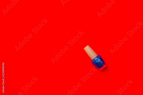Bottle of nail polish on red background with copy space