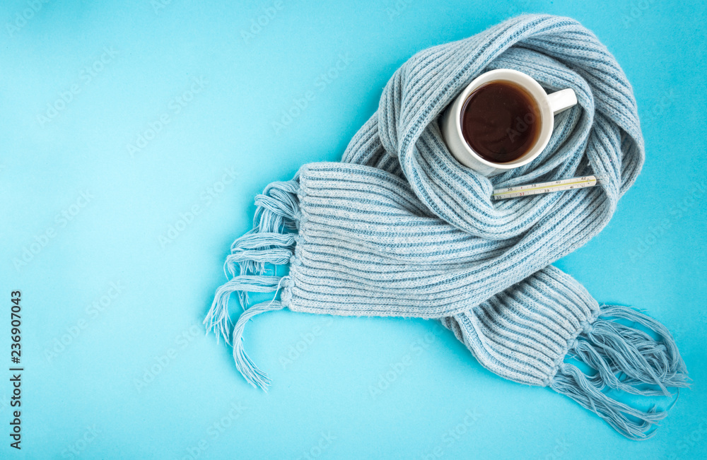 White mug of tea with blue scarf and thermometer on blue background. Disease and health concept. - obrazy, fototapety, plakaty 