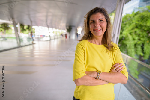 Portrait of happy mature woman smiling outdoors with arms crossed