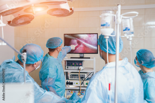 Process of gynecological surgery operation using laparoscopic equipment. Group of surgeons in operating room with surgery equipment photo