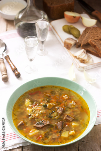 Rassolnik, traditional Russian soup, served with various snacks and vodka. Rustic style.