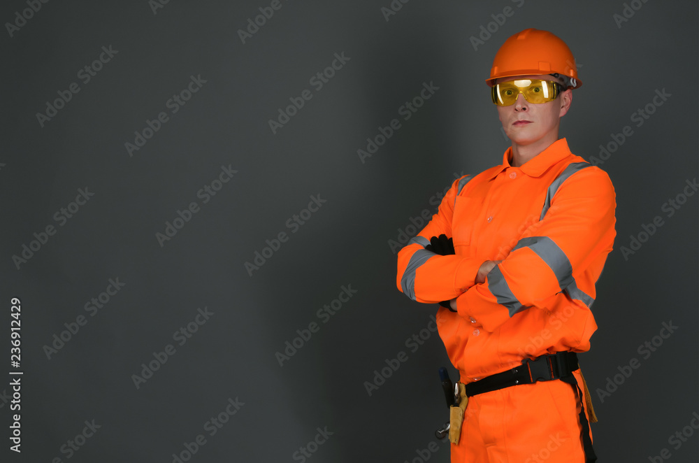 Builder construction worker standing with crossed arms isolated on gray background with copy space. Under construction concept background. Builder construction worker standing with crossed arms isolated on gray background with copy space. Under construction concept background.