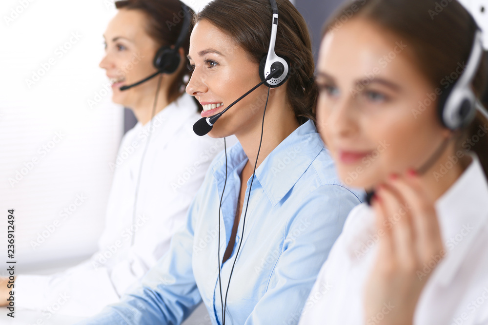 Call center. Group of operators at work. Focus at beautiful business woman in headset Call center. Group of operators at work. Focus at beautiful business woman in headset