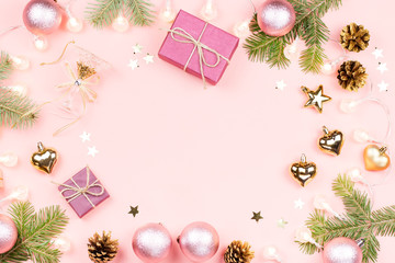 Christmas background with fir branches, lights, pink decorations on pink