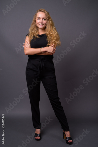 Young beautiful businesswoman with long wavy blond hair against 