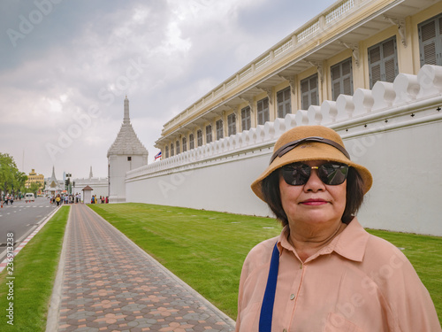 Portrait senior asian women With Wat Phrakeaw Temple wall in the main Temple of bangkok Capital of Thailand photo