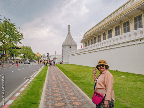 Portrait senior asian women With Wat Phrakeaw Temple wall in the main Temple of bangkok Capital of Thailand