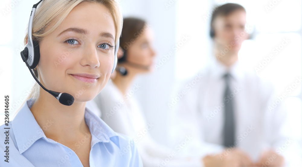 Call center. Group of operators at work. Focus at blonde business woman in headset Call center. Group of operators at work. Focus at blonde business woman in headset