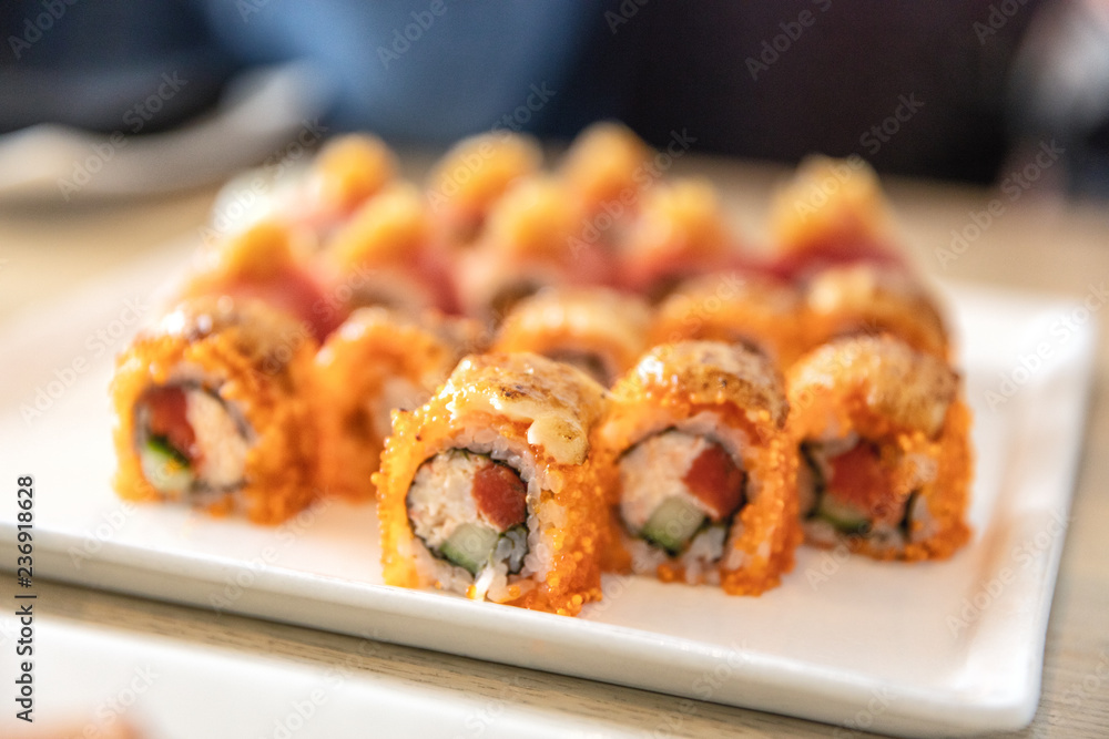 Sushi roll of maguro tuna topped with salmon roe at luxury high end japanese restaurant. Plate of sushis. Sushi roll of maguro tuna topped with salmon roe at luxury high end japanese restaurant. Plate of sushis.