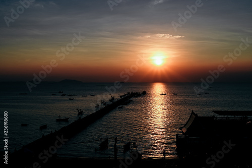 Sunset at the bridge by the sea with a boat surrounded. © nattanan