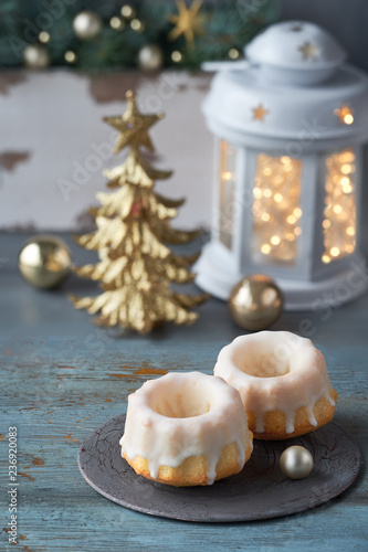 Close-up on bundt cakes on rustic green table with Christmas lights in white lantern and Xmas decorations