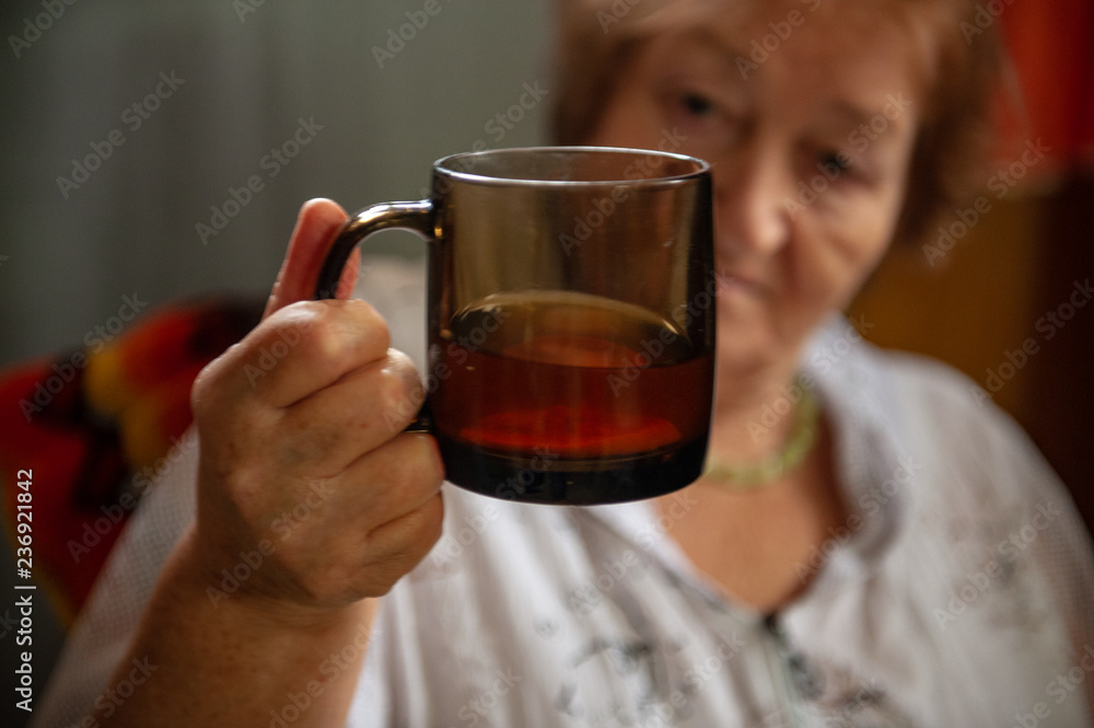 Elderly woman with beautiful wrinkled face is holding glass of water in her hands to wash down  medication.