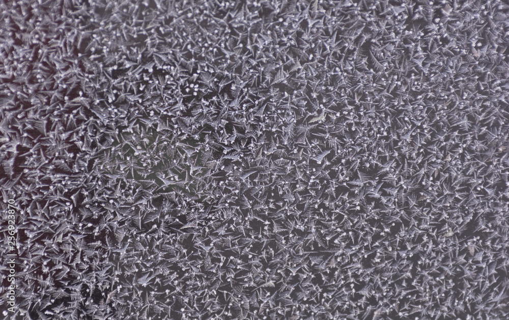 Snowflakes on window glass in winter blue texture on window. Abstract icy festive background. Close-up. Soft focus Snowflakes on window glass in winter blue texture on window. Abstract icy festive background. Close-up. Soft focus