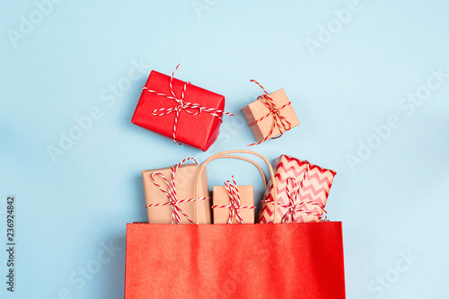 Red shopping bag with gifts on a blue background.