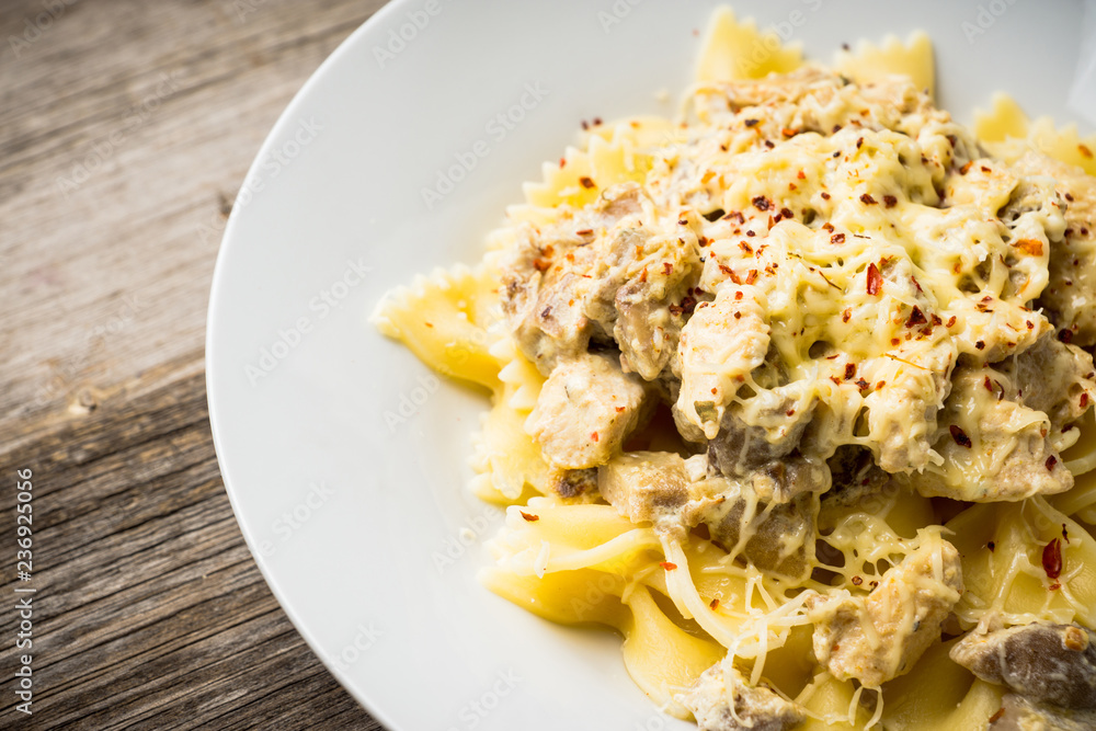Fresh pasta with chicken, mushrooms and cheese on the rustic wooden background. Selective focus. Fresh pasta with chicken, mushrooms and cheese on the rustic wooden background. Selective focus.