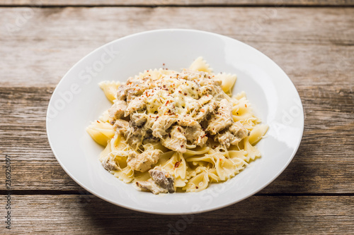 Fresh pasta with chicken, mushrooms and cheese on the rustic wooden background. Selective focus.