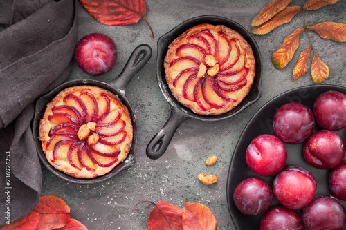 Homemade crumble tarts with plum slices baked in small iron skillets