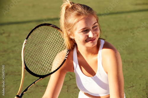 Girl and tennis racket, looking away