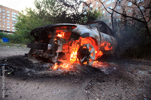 Valokuvatapetti burning civilian car in the city, War actions aftermath, Ukraine and Donbass con