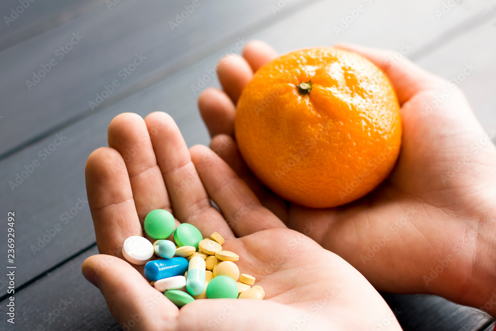Humans hands with pills and mandarin fruit. Male hand holding pills and fruits. Vegan choice. Health food. No pills. Humans hands with pills and mandarin fruit. Male hand holding pills and fruits. Vegan choice. Health food. No pills.
