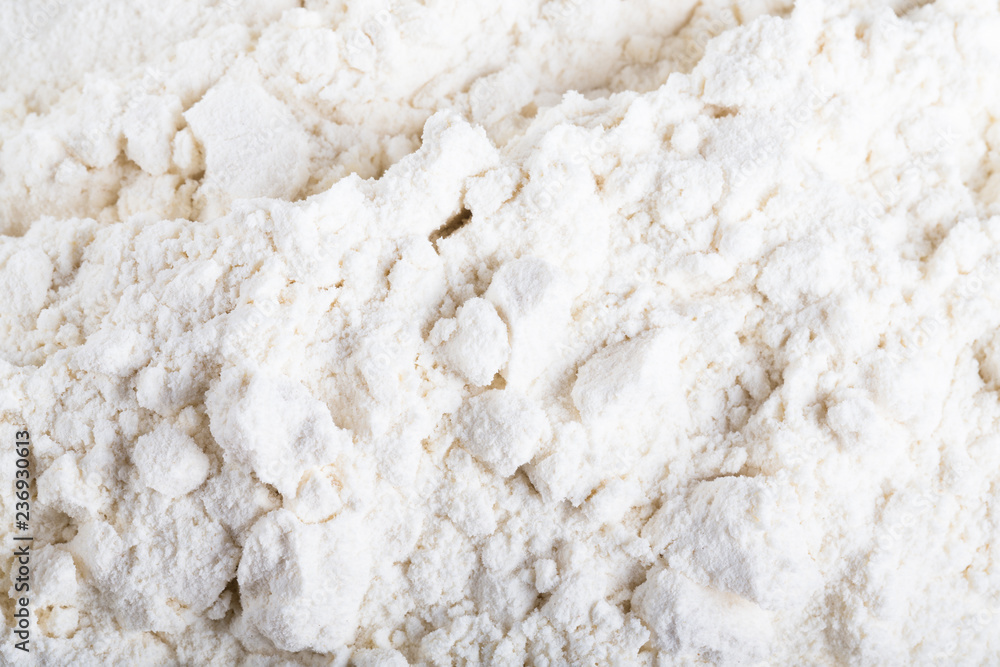 Pile of white wheat flour is scattered on an old worn cutting board Pile of white wheat flour is scattered on an old worn cutting board
