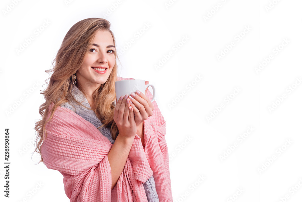 Attractive blonde woman wraped in blanket holding cup of hot beverage isolated on white with copyspace. Winter holidays, cozy homestay.