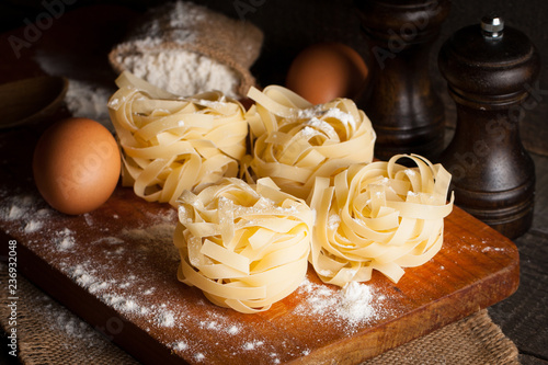 Closeup of raw homemade pasta with ingredients on wooden, rustic background. Pasta, salt, eggs, yolk, pepper. Home made food concept.