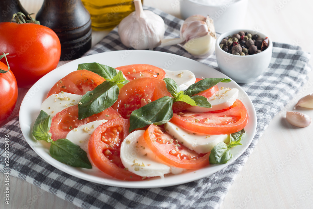 Photo of Caprese Salad with tomatoes, basil, mozzarella, olives and olive oil on wooden background. Italian traditional caprese salad ingredients. Mediterranean, organic and natural food concept. Photo of Caprese Salad with tomatoes, basil, mozzarella, olives and olive oil on wooden background. Italian traditional caprese salad ingredients. Mediterranean, organic and natural food concept.