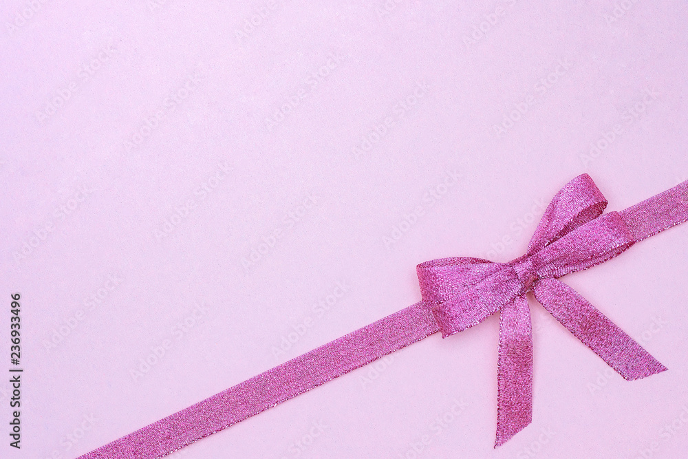 Decorative shiny ribbon with bow on pastel pink background with copy space for text, Top view, Layout.