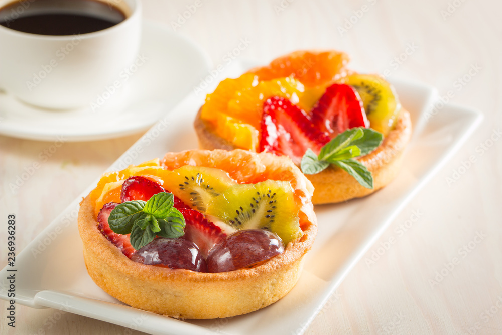 Photo of a fruit and berry tart dessert with toss sugar on wooden background. Fresh delicious sweet cake with raspberries, grapes, strawberries, cherry, kiwi, grapefruit and cream. Photo of a fruit and berry tart dessert with toss sugar on wooden background. Fresh delicious sweet cake with raspberries, grapes, strawberries, cherry, kiwi, grapefruit and cream.