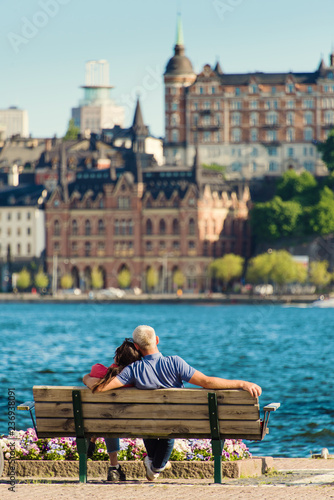 Couple on a bench, summer view of the Old Town pier architecture in Stockholm. Sweden