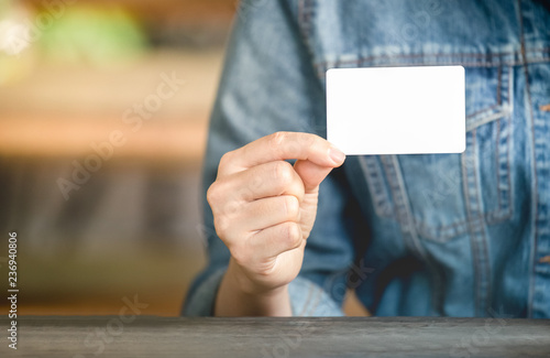 Women's Jean jecket is hand holding white business card for contact works. Blank paper card mock up photo