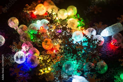 Colored light bulbs and golden snowflakes on black.
