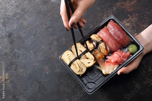 Sushi na wynos. Jedzenie sushi pałeczkami prosto z tacki.