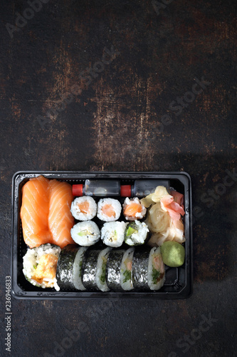 Sushi na wynos. Tacka z kawałkami sushi , imbirem , wasabi i sosem sojowym na ciemnym tle.